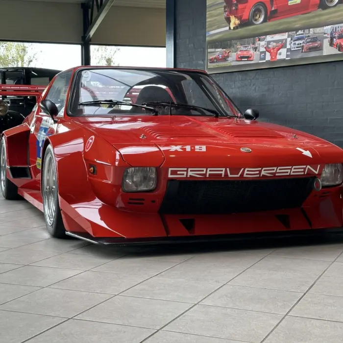 Roter, stark verbreiterter Fiat X1/9 als Rennwagen mit Graversen-Schriftzug in einer Ausstellungshalle.